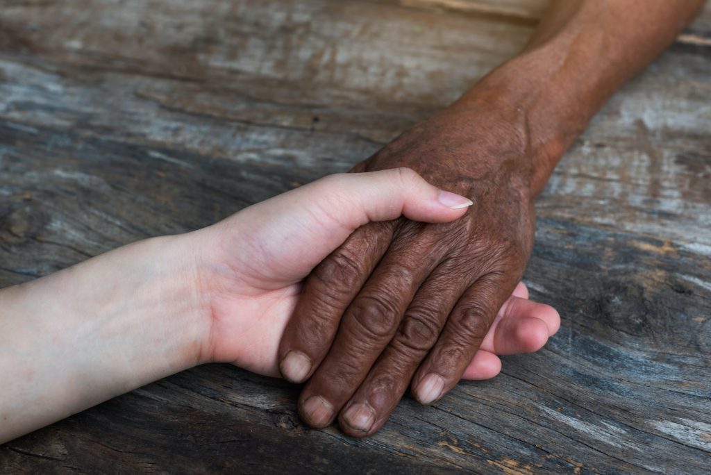 Close-up of elderly caregiver and daughter's hands.