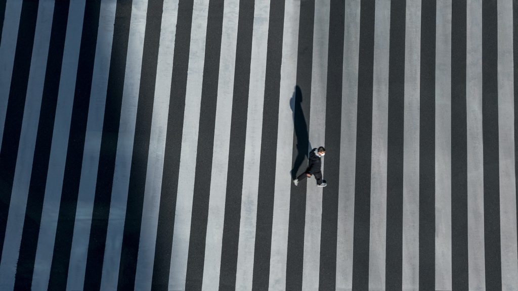 Elevated view over a man on pedestrian crossing in road intersection of Japan.