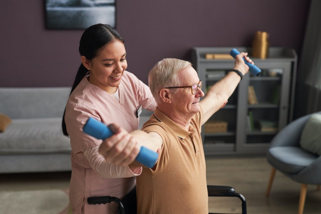 Social worker helping senior man to exercise