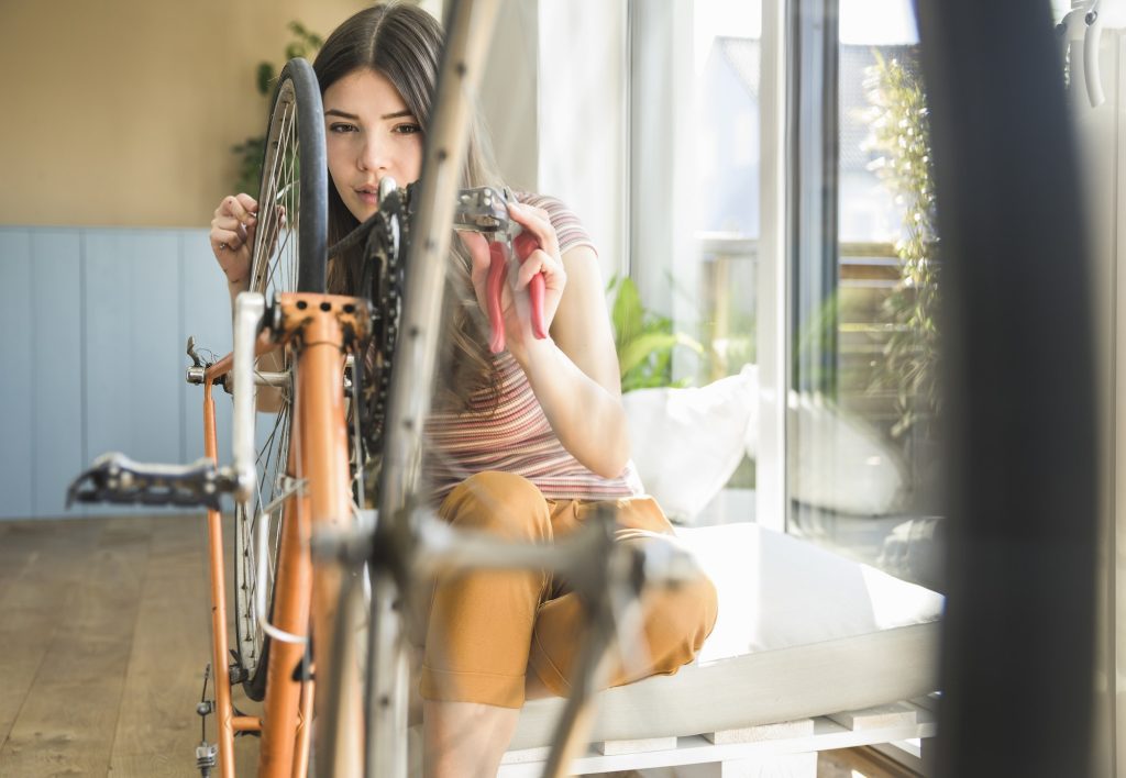 Young woman reparing bicycle at home