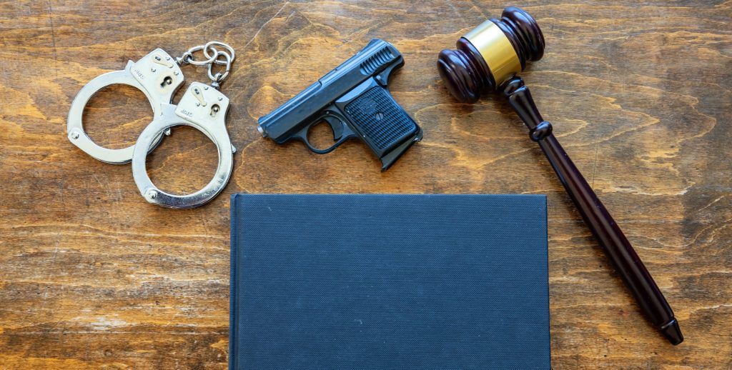 Law, crime, punishment concept. Judge gavel, handgun, handcuffs and a black blank legal book