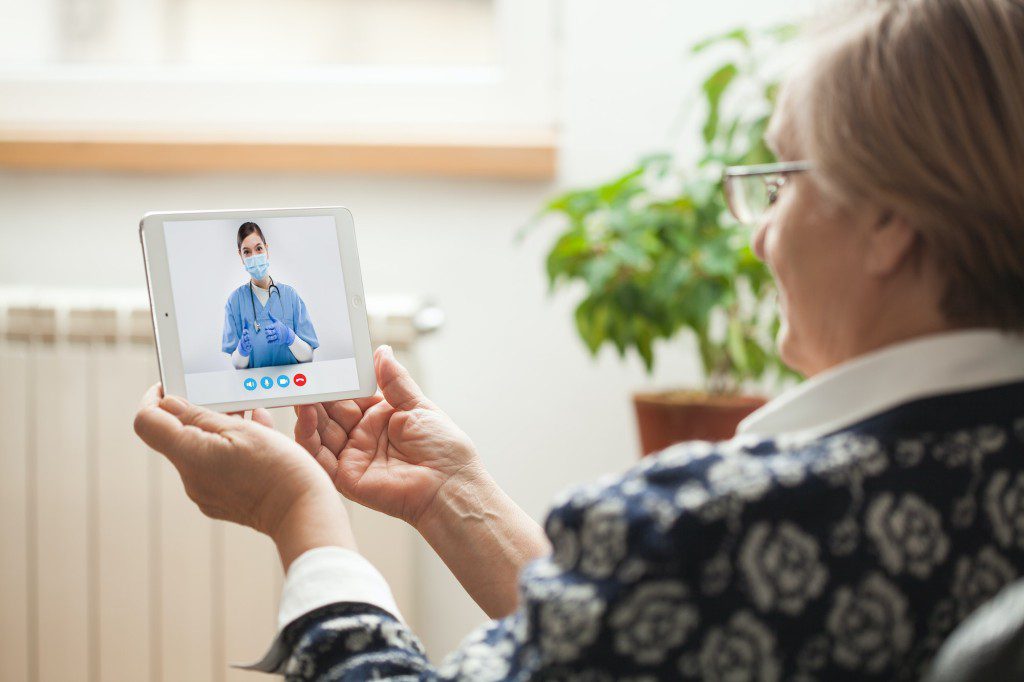Elderly caucasian woman talking to young female e-doctor via online video chat