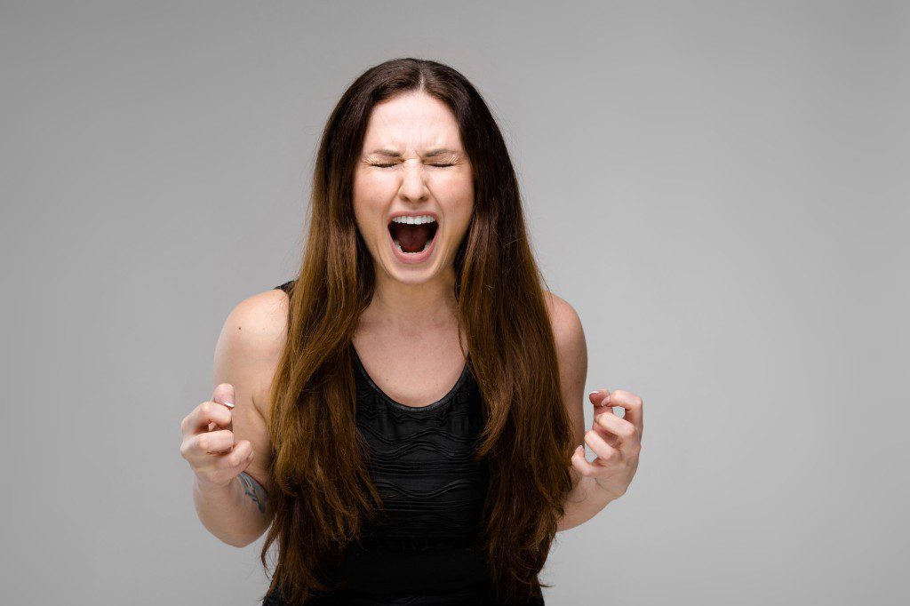 Emotional plus size model standing in studio with open mouth screaming showing agression anger want