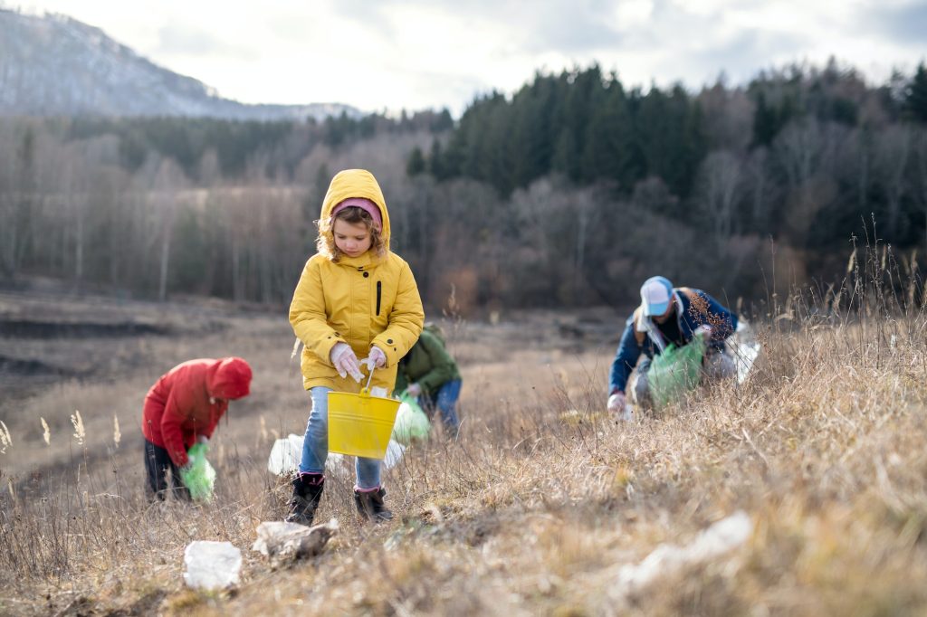 Group of activists picking up litter in nature, environmental pollution concept