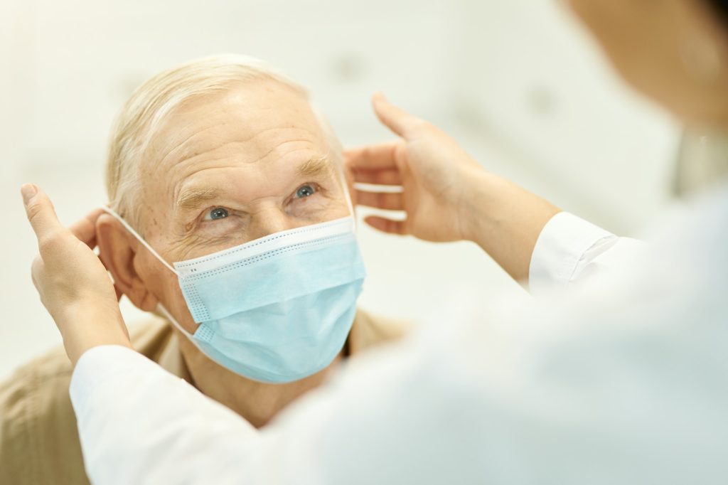 Healthcare worker putting mask on a senior patient