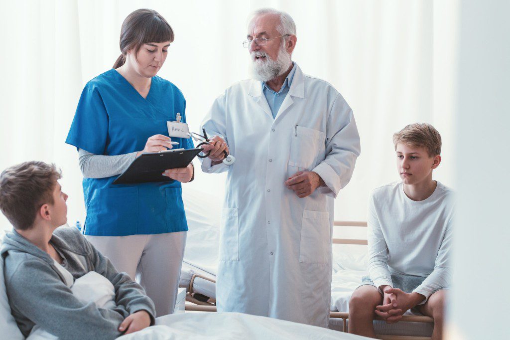 Intern and doctor writing something on legal pad during hospital visit