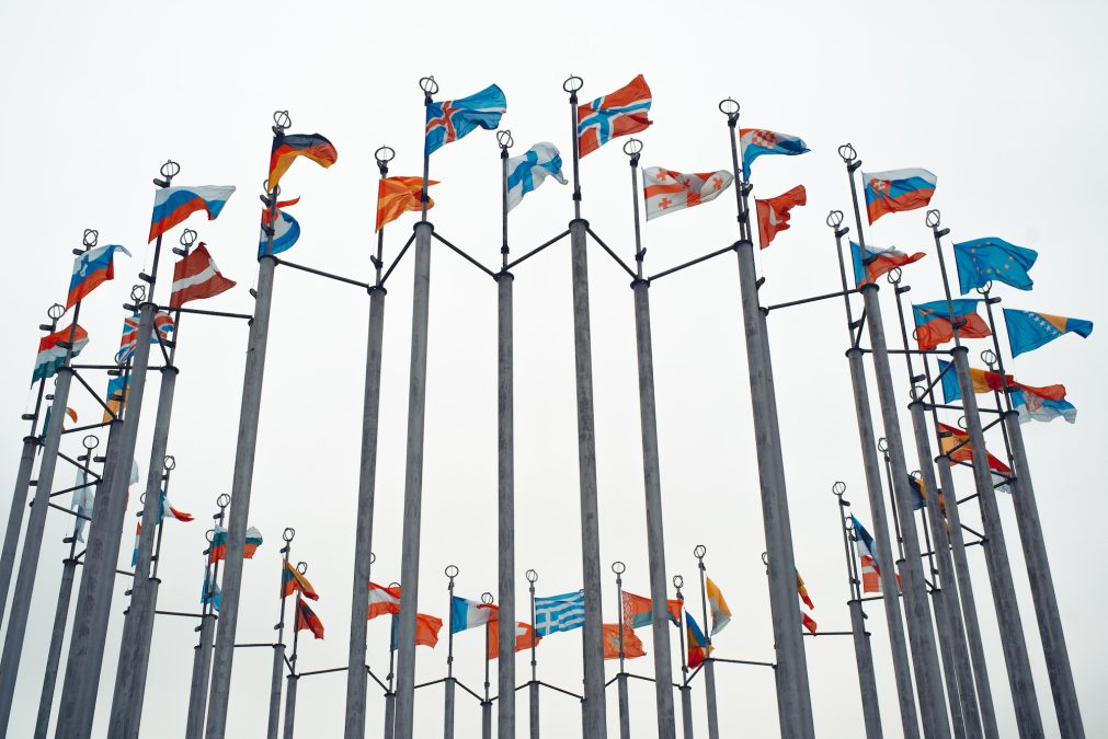 International flags of many countries of the world waving on poles outdoors against a gray sky, low