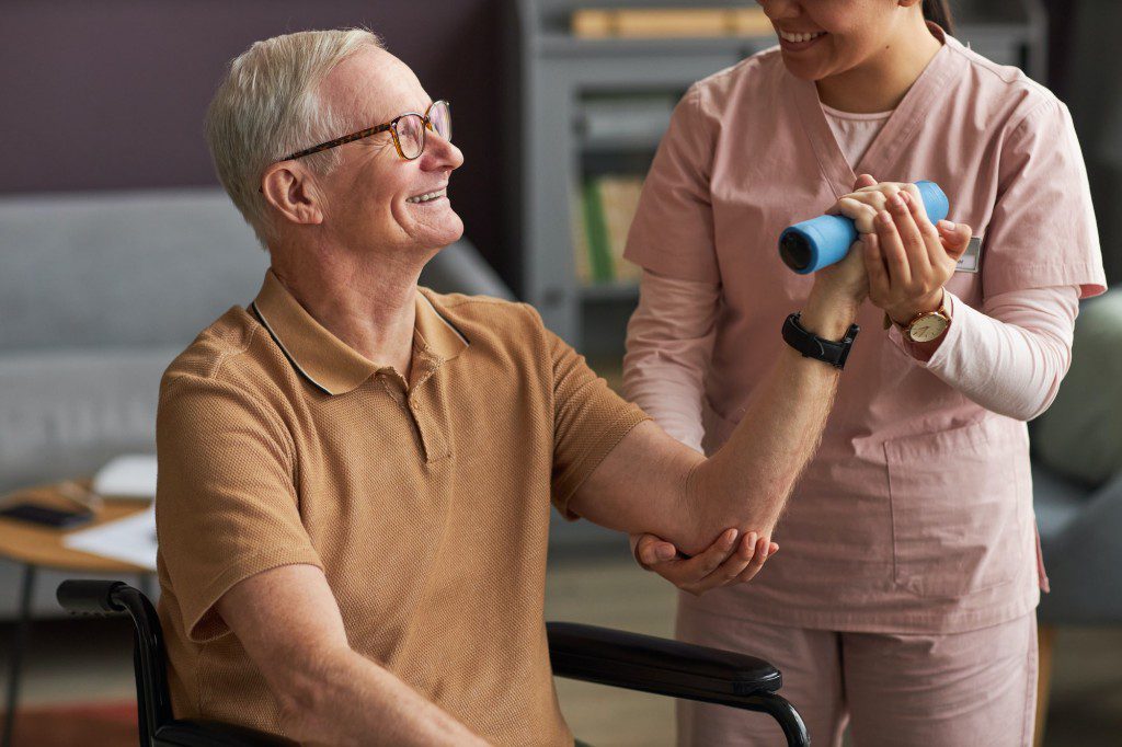 Senior man exercising with caregiver