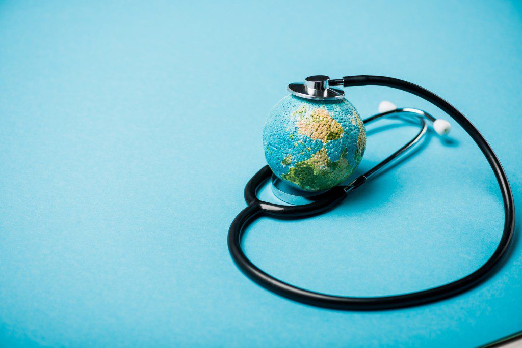 Stethoscope with globe on blue background, world health day concept