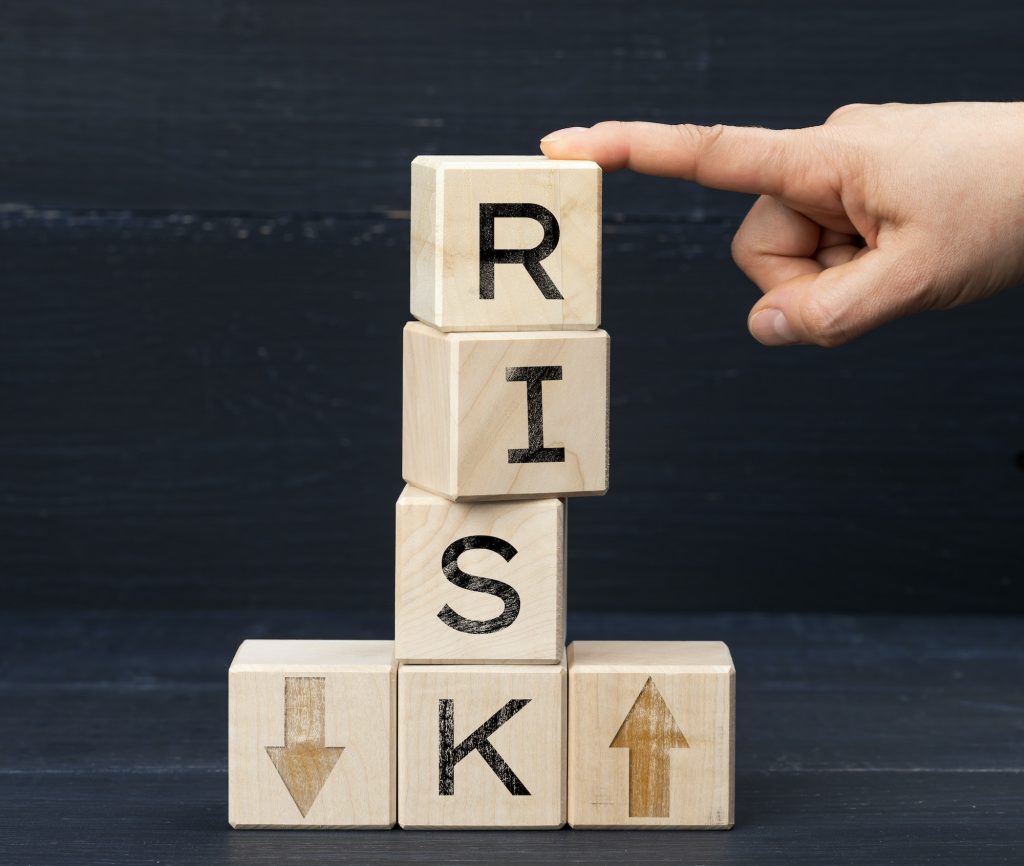 Wooden cubes with the inscription risk on a blue background. Risk reduction concept, reinsurance