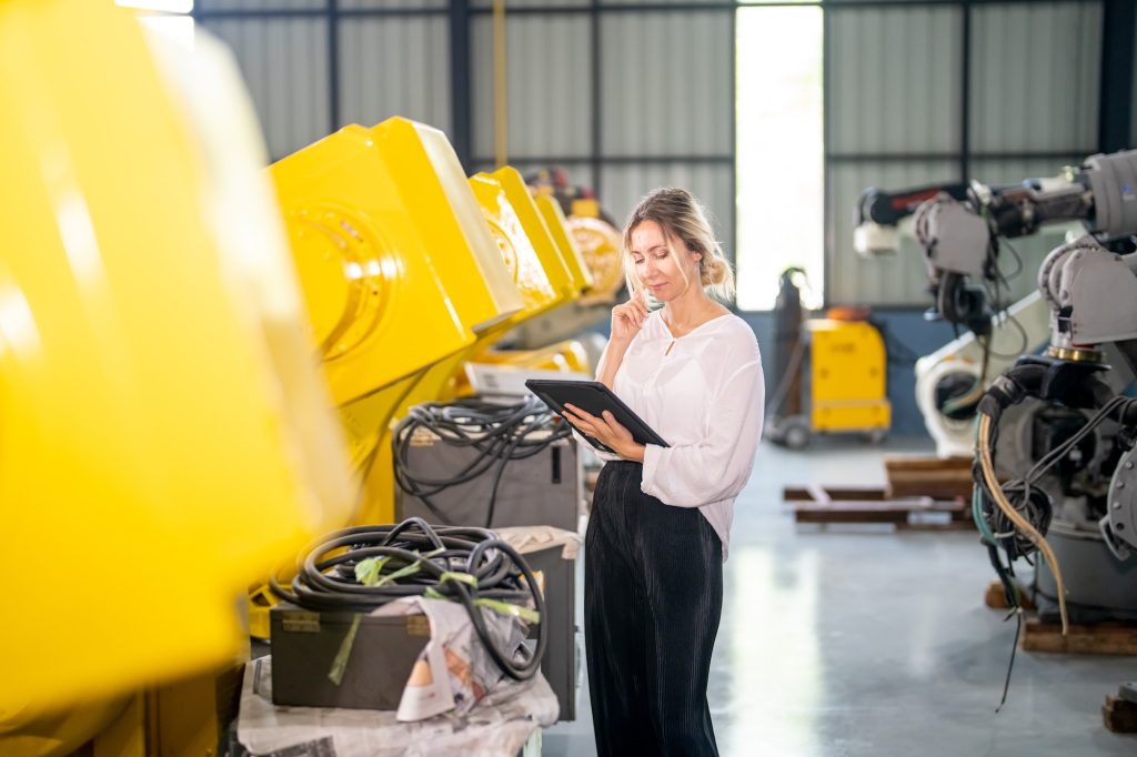 Engineer inspecting automatic AI robot arm and machines in factory. Engineer inspecting automatic AI