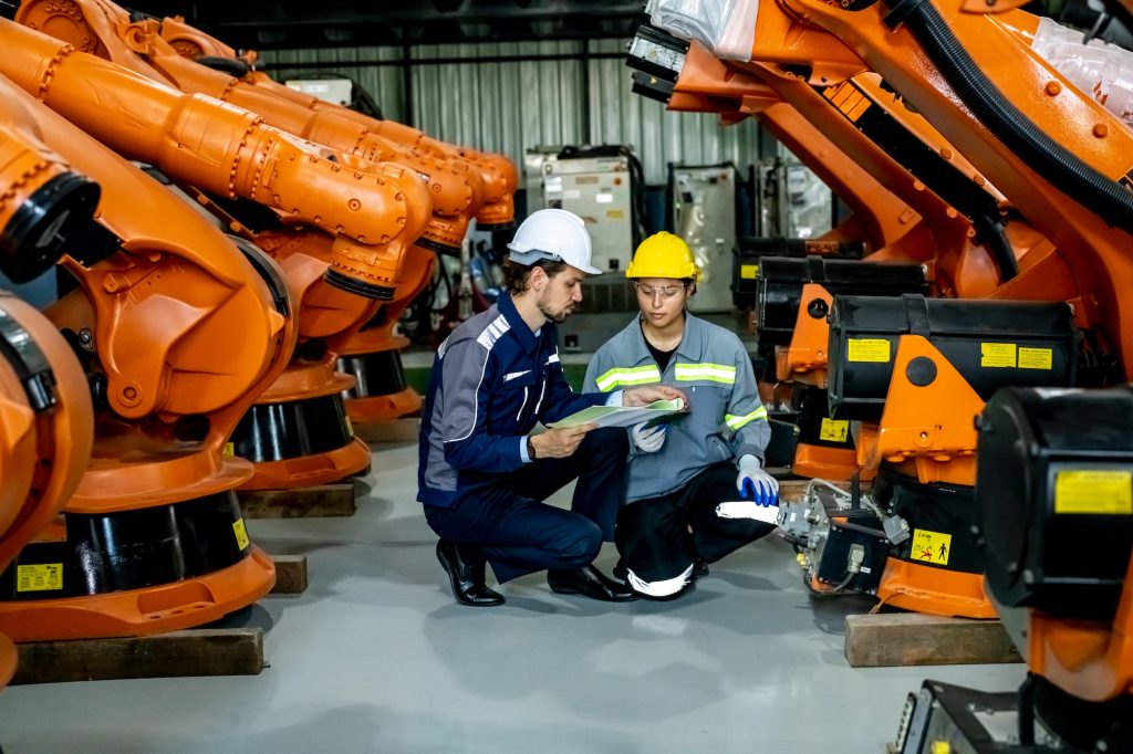 Engineer inspecting automatic AI robot arm and machines in factory. Engineer inspecting automatic AI