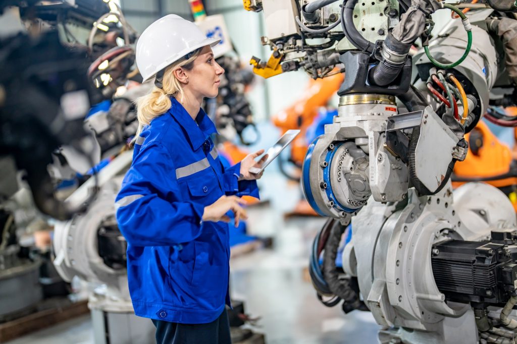 Engineer inspecting automatic AI robot arm and machines in factory. Engineer inspecting automatic AI