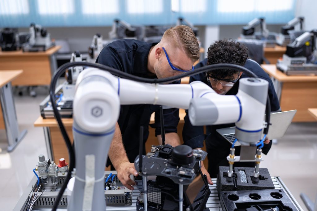 Engineer sitting in robot fabrication room quality checking robot arm hardware engineering