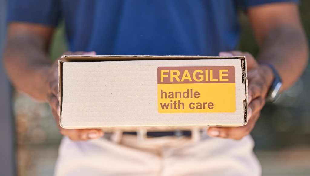 Hands, logistics and box for special delivery, cargo or handle with care in transport or shipping.