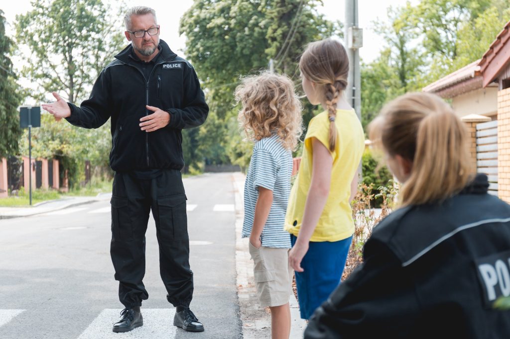 Handsome policeman explains to children the rules of safe movement on the street