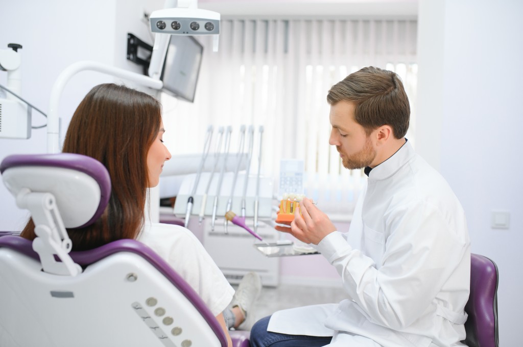 The concept of diagnosis and treatment of tooth disease. Doctor shows a model of a sick tooth.