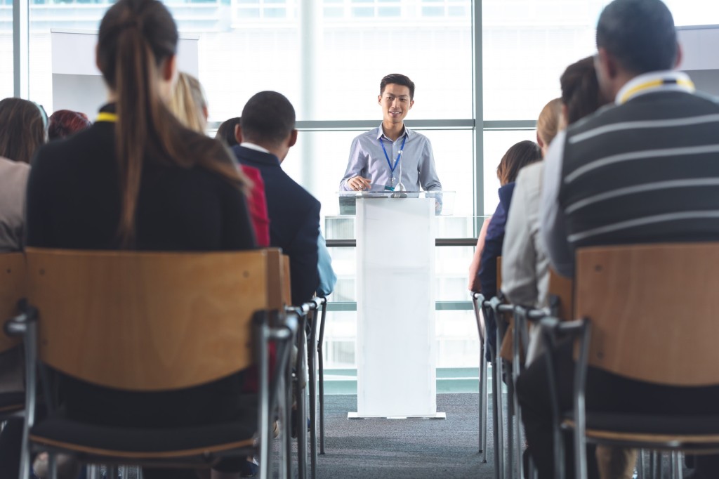 Businessman speaking in front of business professionals at business seminar in office building