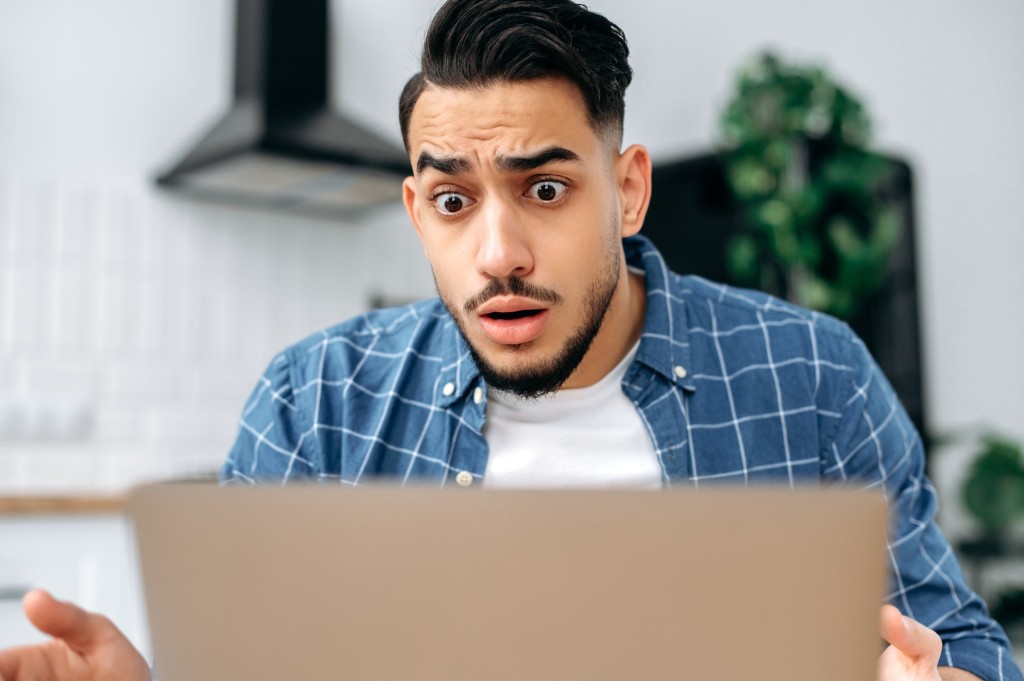 Close-up of confused puzzled indian or arabian guy, freelancer or student, looking disappointment at