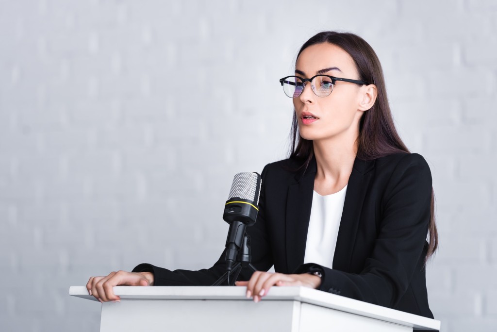 nervous lecturer in glasses standing on podium tribune and looking away