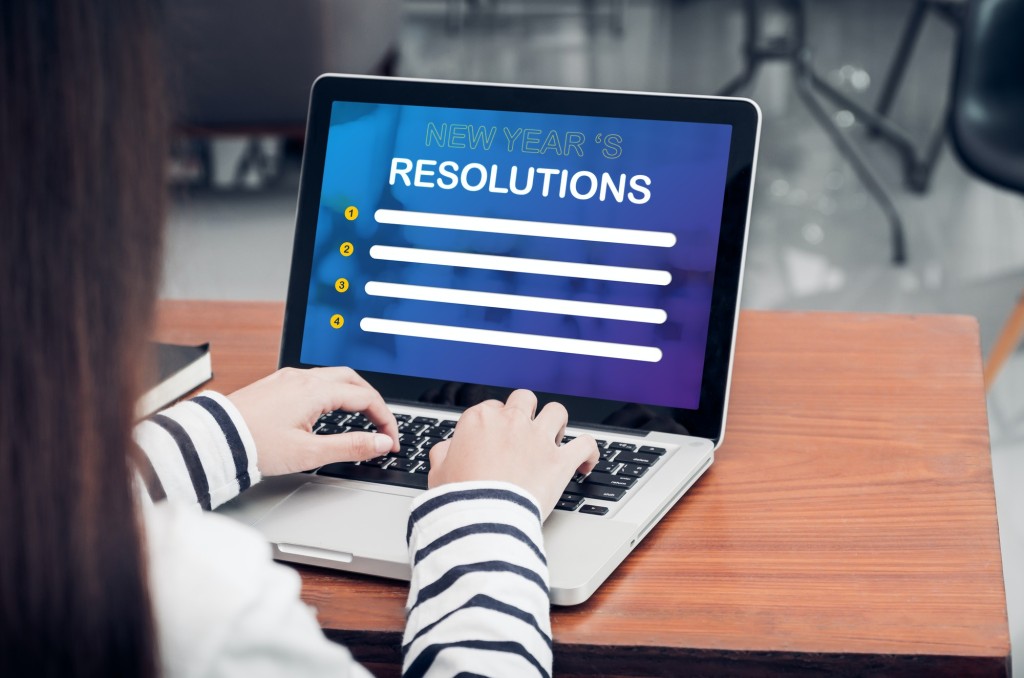 woman type new year resolutions on laptop and looking new year resolution