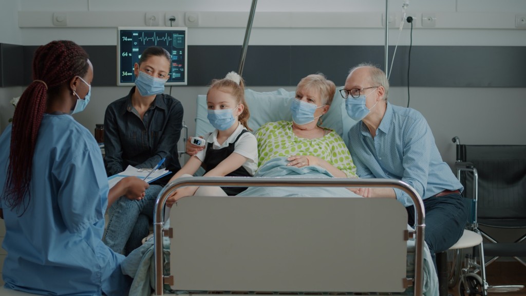 Medical assistant explaining diagnosis to patient and family in hospital ward