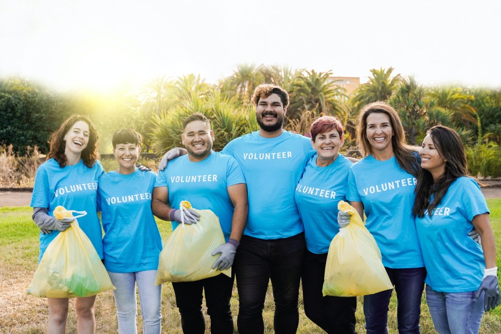 Multi generational volunteers picking up plastic trash waste at park city