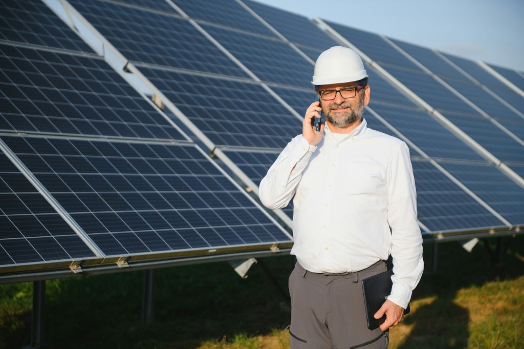Solar power plant. Man standing near solar panels. Renewable energy