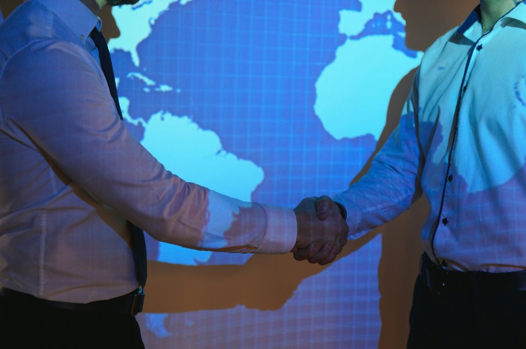 Handshake with map of the world in background. two businessmen on the background of the world map