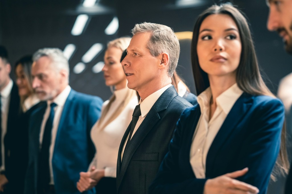 The five businesspeople standing indoor.