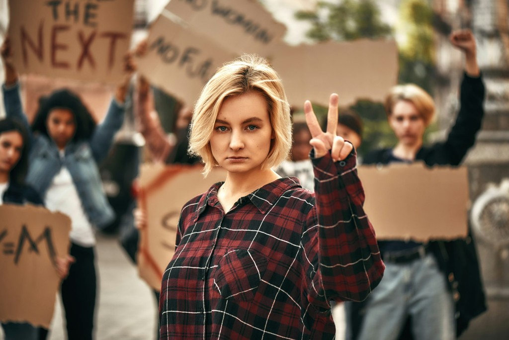 We want peace Young blonde woman is showing piece sign while protesting with female activists